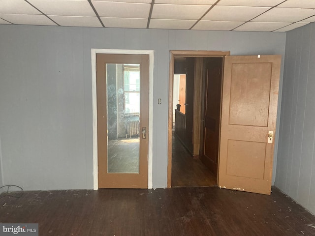 unfurnished room featuring a paneled ceiling and dark hardwood / wood-style flooring