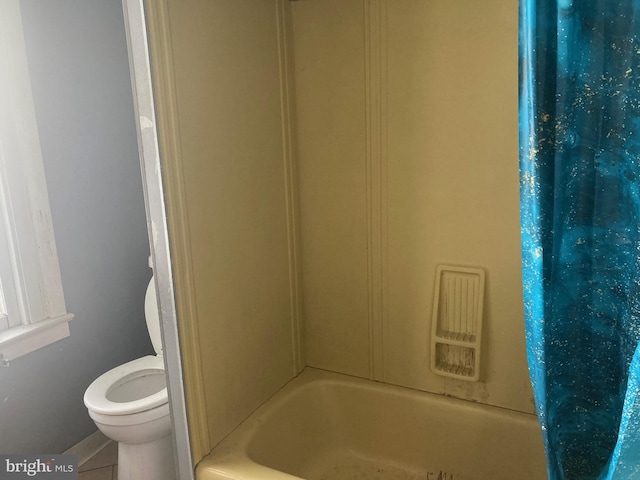 bathroom featuring tile patterned flooring, shower / tub combo, and toilet