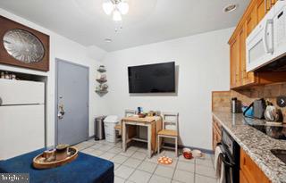 kitchen featuring black oven, light stone countertops, and light tile patterned floors