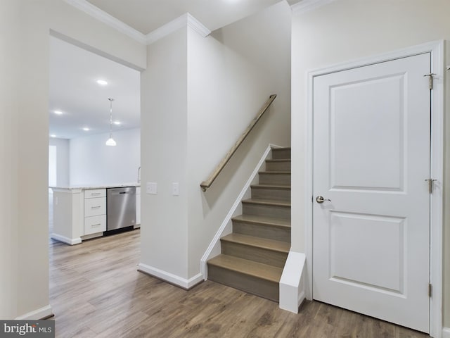 stairs with wood-type flooring and ornamental molding