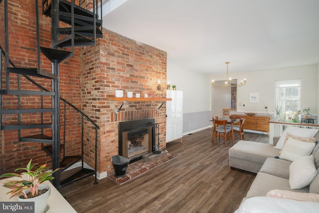 living room with a notable chandelier, brick wall, dark hardwood / wood-style floors, and a fireplace