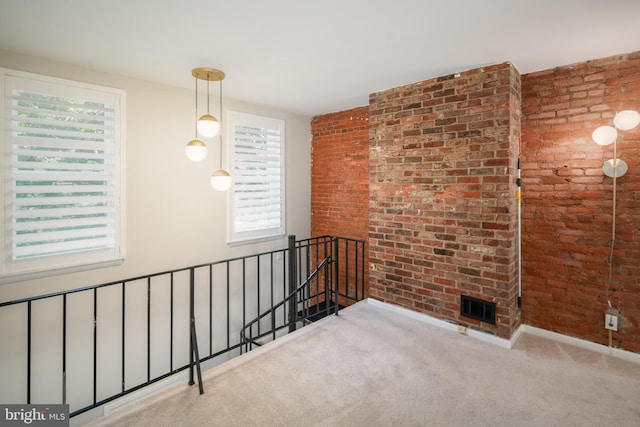 empty room with light carpet, a wealth of natural light, and brick wall