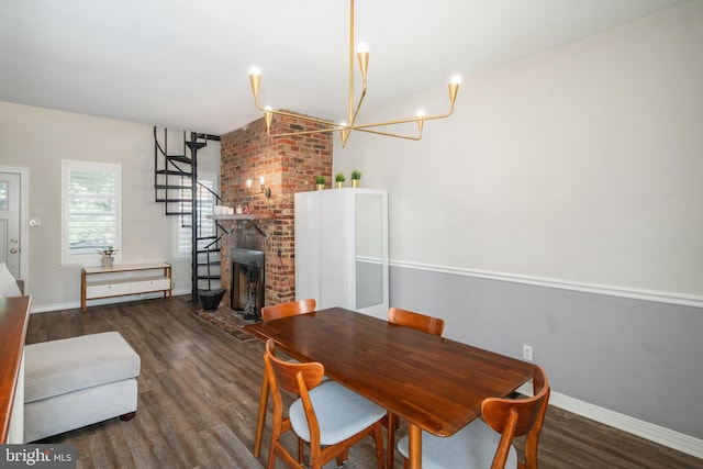 dining space featuring a brick fireplace, a notable chandelier, and dark wood-type flooring