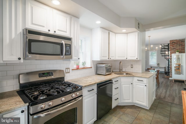 kitchen featuring white cabinets, hanging light fixtures, sink, a chandelier, and appliances with stainless steel finishes