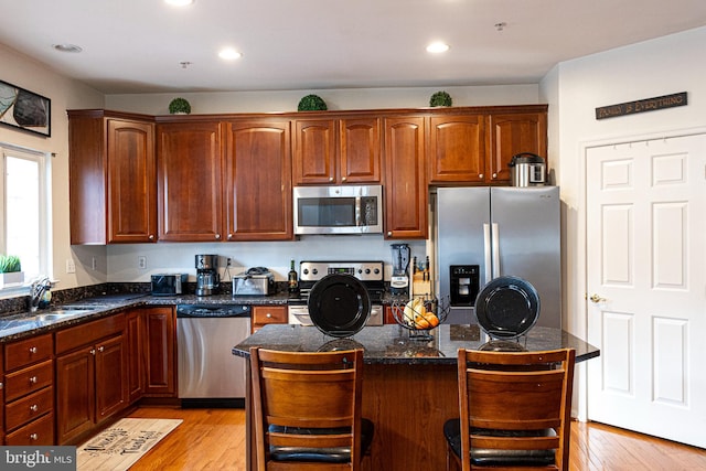 kitchen featuring appliances with stainless steel finishes, light wood-type flooring, a breakfast bar area, and sink