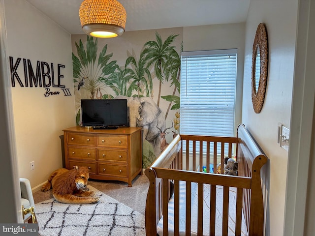 bedroom with light colored carpet and a nursery area