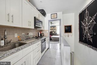 kitchen featuring stainless steel appliances, white cabinetry, sink, and tasteful backsplash