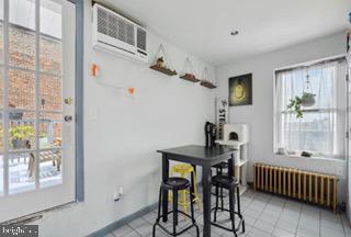 tiled dining area with a wall unit AC and radiator heating unit