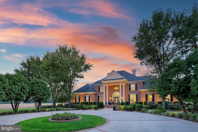 neoclassical home featuring covered porch and a yard