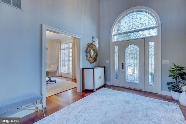 foyer entrance featuring a towering ceiling and dark hardwood / wood-style flooring