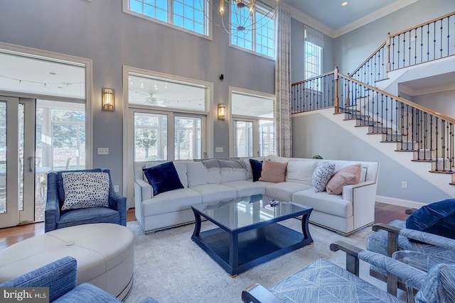 living room featuring a notable chandelier, a towering ceiling, light hardwood / wood-style flooring, and ornamental molding