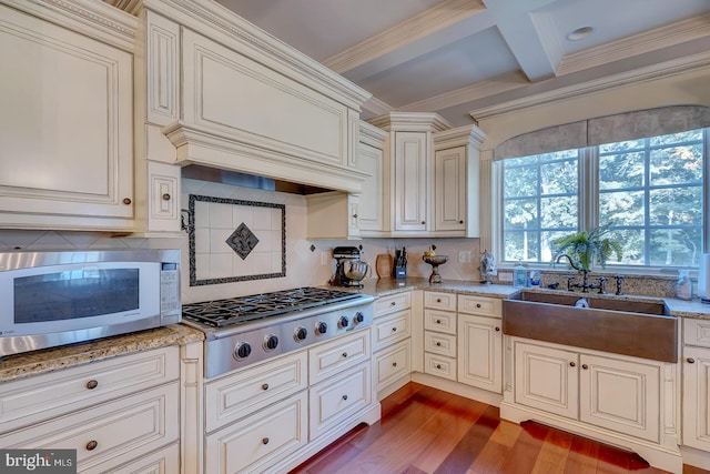 kitchen featuring appliances with stainless steel finishes, light wood-type flooring, backsplash, coffered ceiling, and beamed ceiling