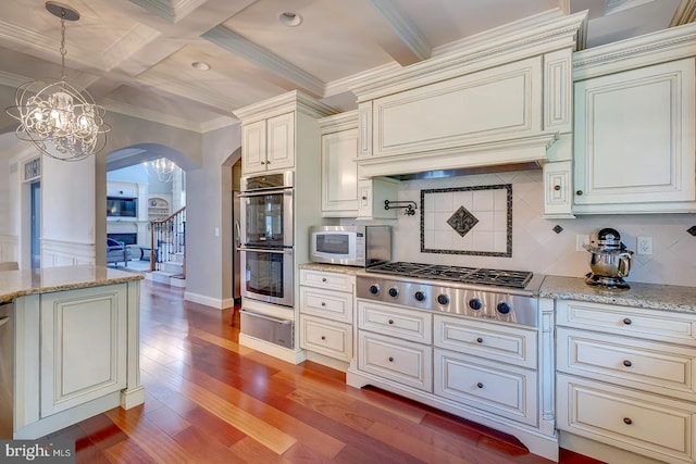 kitchen with custom range hood, stainless steel appliances, decorative light fixtures, light wood-type flooring, and tasteful backsplash