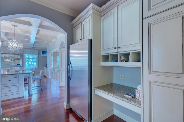 kitchen featuring dark hardwood / wood-style floors, light stone counters, coffered ceiling, and stainless steel refrigerator