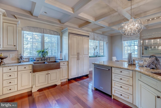 kitchen with cream cabinets, hardwood / wood-style floors, decorative light fixtures, stainless steel dishwasher, and a chandelier