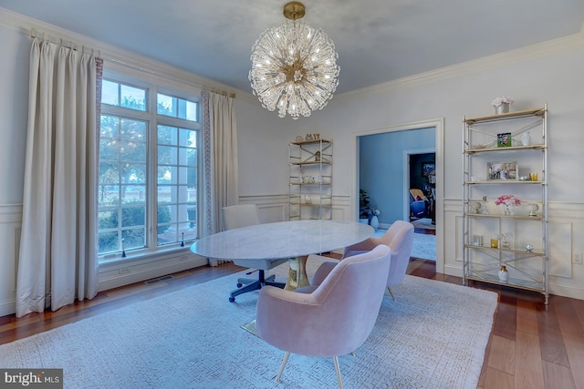 dining area with ornamental molding, a notable chandelier, and wood-type flooring