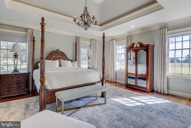 bedroom featuring multiple windows, light wood-type flooring, and a raised ceiling