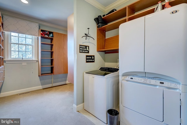 clothes washing area featuring crown molding, light carpet, washing machine and dryer, and cabinets