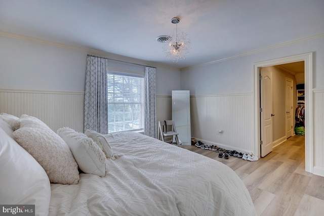 bedroom featuring an inviting chandelier, light hardwood / wood-style flooring, and ornamental molding