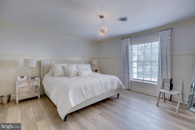 bedroom with light hardwood / wood-style floors, ornamental molding, and a chandelier