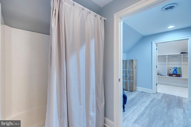 bathroom featuring shower / tub combo with curtain, wood-type flooring, and lofted ceiling