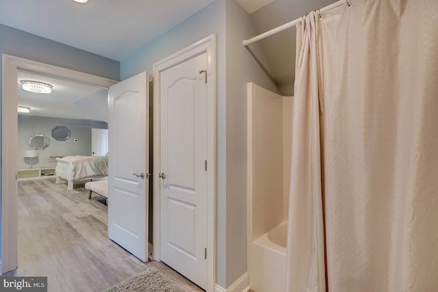 bathroom featuring wood-type flooring and shower / bath combo with shower curtain