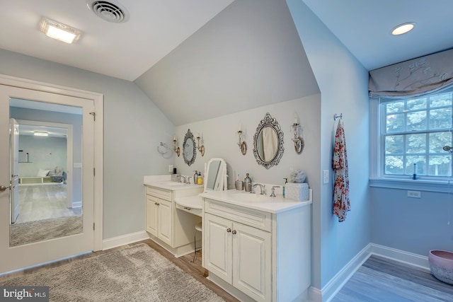 bathroom with vanity, wood-type flooring, and lofted ceiling