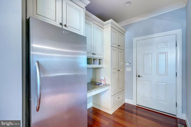 kitchen with built in desk, dark hardwood / wood-style flooring, stainless steel refrigerator, crown molding, and light stone counters