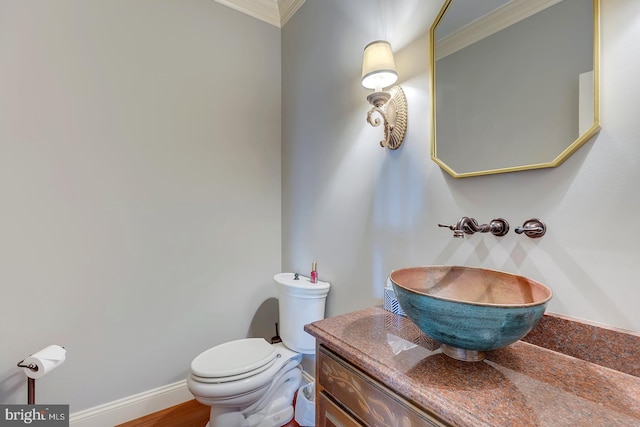 bathroom with toilet, crown molding, hardwood / wood-style floors, and vanity