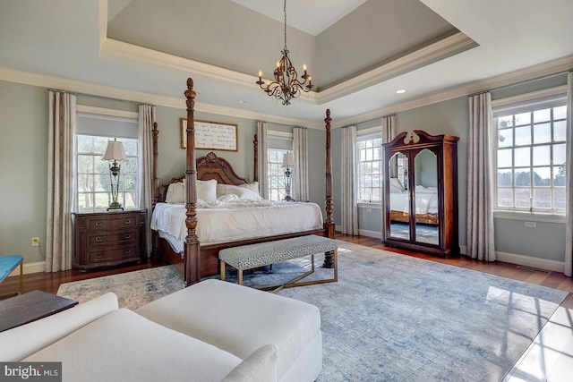 bedroom featuring multiple windows, light wood-type flooring, and a raised ceiling