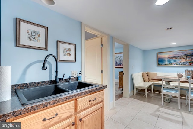 kitchen with light tile patterned floors, light brown cabinetry, and sink