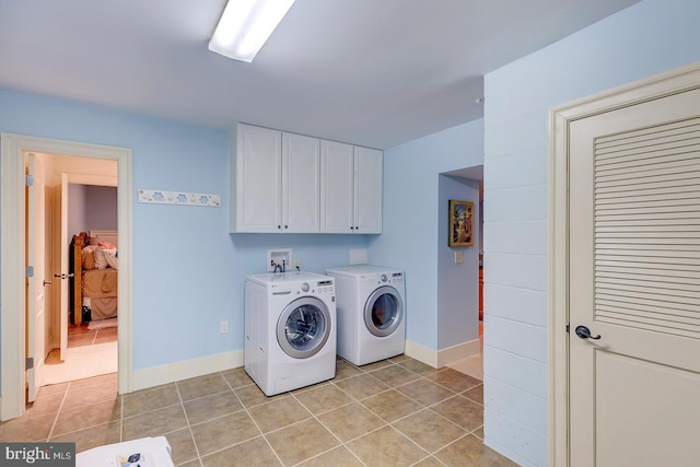 washroom with light tile patterned floors, washing machine and dryer, and cabinets