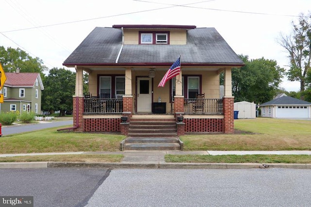 view of front of home with a front yard, an outdoor structure, and a porch