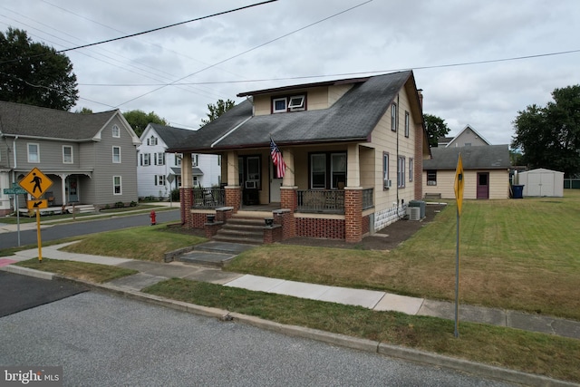 bungalow-style house featuring a front yard, a storage shed, covered porch, and central air condition unit