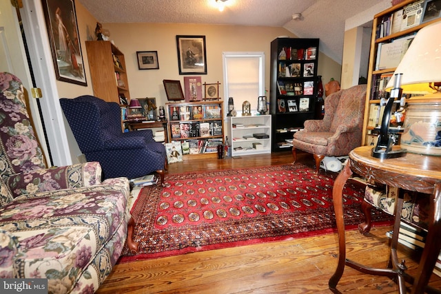 living room featuring vaulted ceiling, a textured ceiling, and hardwood / wood-style floors