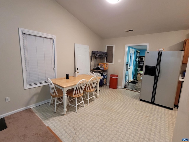 dining area featuring light colored carpet and vaulted ceiling