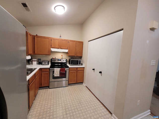 kitchen with lofted ceiling, appliances with stainless steel finishes, and sink