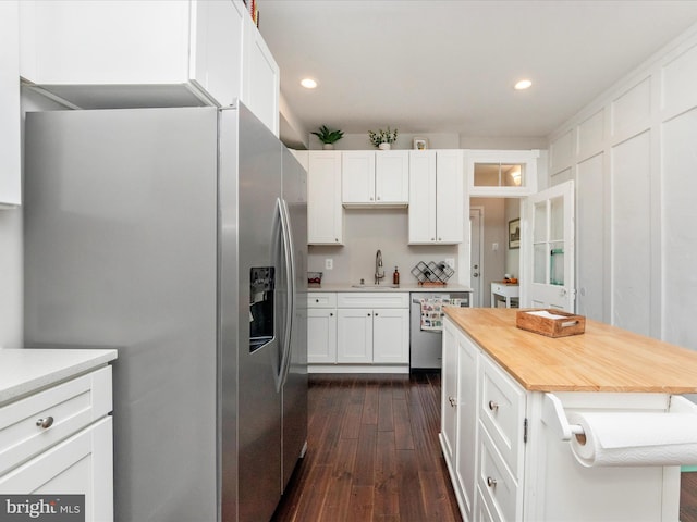 kitchen featuring dark wood-type flooring, sink, white cabinetry, stainless steel appliances, and backsplash