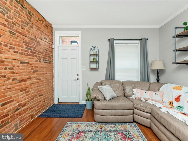 living room with brick wall, hardwood / wood-style flooring, and ornamental molding