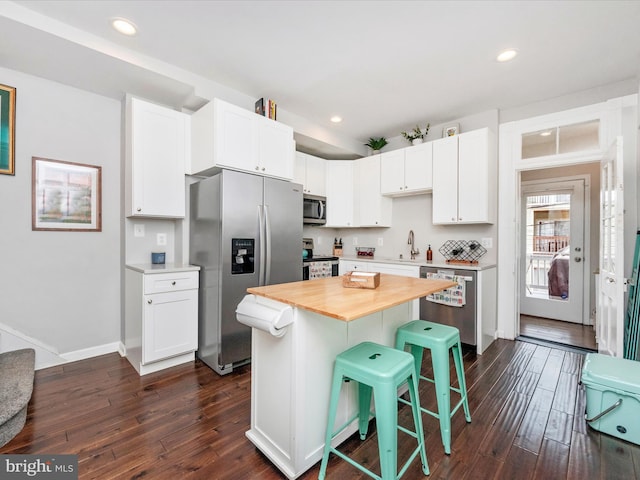 kitchen featuring a breakfast bar, stainless steel appliances, white cabinets, and a center island