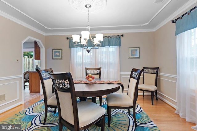 dining room with crown molding, a chandelier, and light wood-type flooring