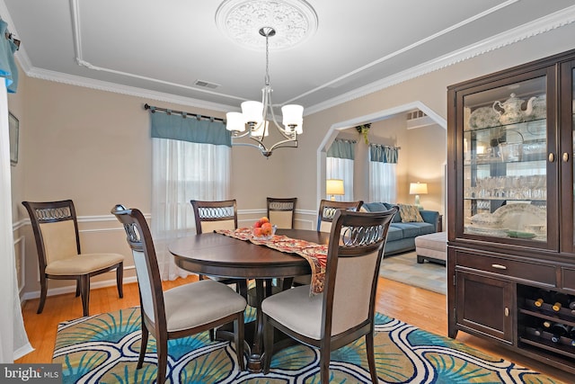 dining room featuring crown molding, an inviting chandelier, and light wood-type flooring