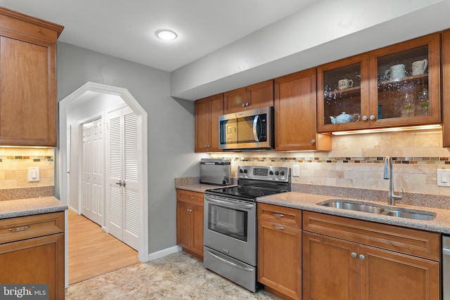 kitchen featuring appliances with stainless steel finishes, sink, backsplash, and light stone counters