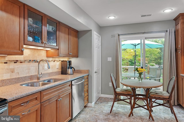 kitchen with light stone counters, sink, decorative backsplash, and stainless steel dishwasher