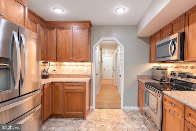 kitchen featuring tasteful backsplash, appliances with stainless steel finishes, and light stone countertops