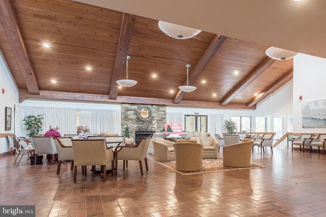 dining area with beamed ceiling, wood ceiling, a stone fireplace, and high vaulted ceiling