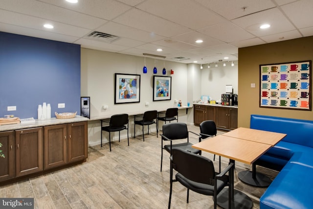 office space with a drop ceiling and light wood-type flooring