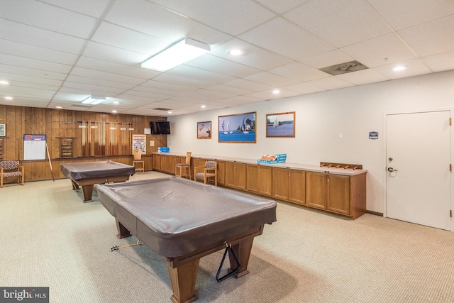 recreation room featuring light carpet, a drop ceiling, pool table, and wood walls