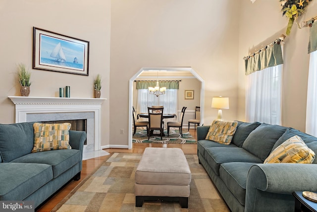 living room featuring a high ceiling, wood-type flooring, a wealth of natural light, and an inviting chandelier