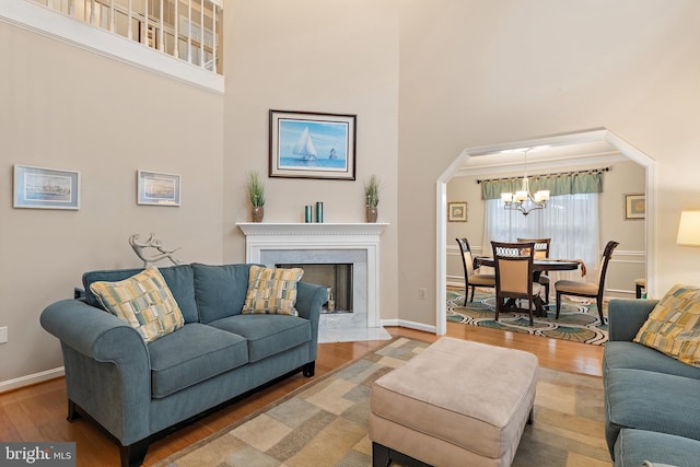 living room with a notable chandelier, hardwood / wood-style flooring, and a towering ceiling